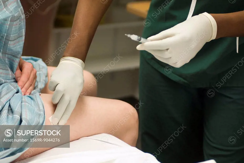 Nurse swabbing patient´s leg after administering a shot