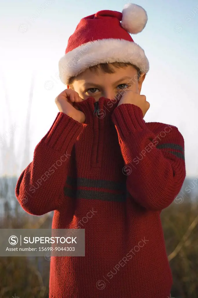 Boy covering face with sweater collar