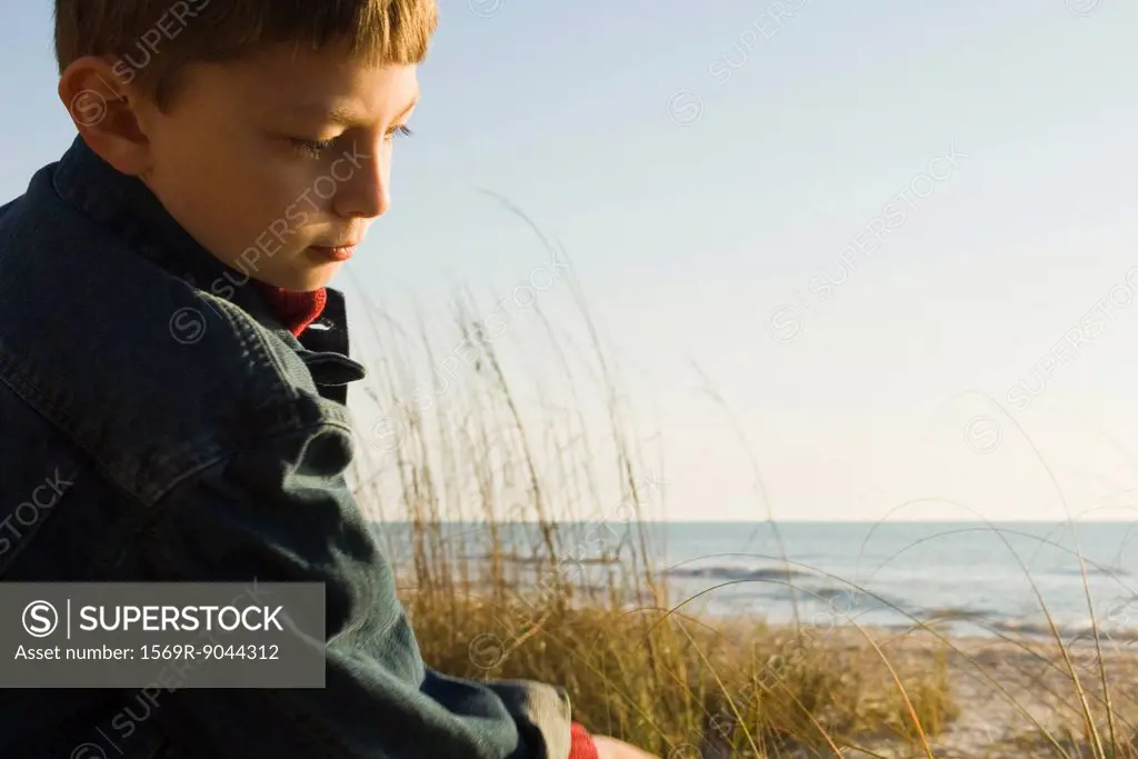 Young boy outdoors contemplatively looking away