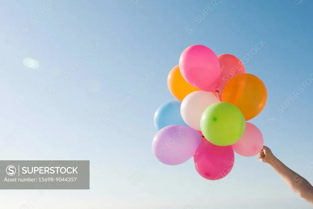 Bunch of helium balloons held aloft against clear blue sky
