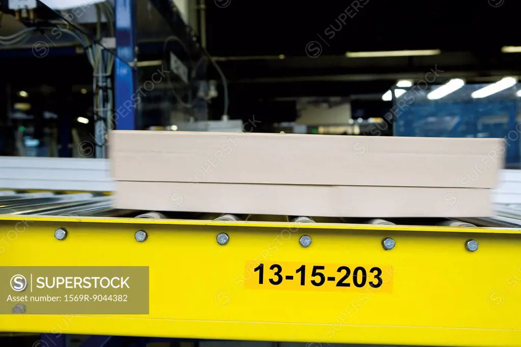 Cardboard box moving along conveyor belt in carpet tile factory