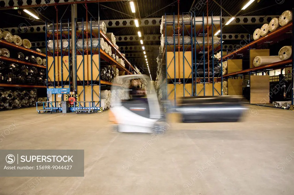 Forklift transporting roll in carpet tile factory warehouse