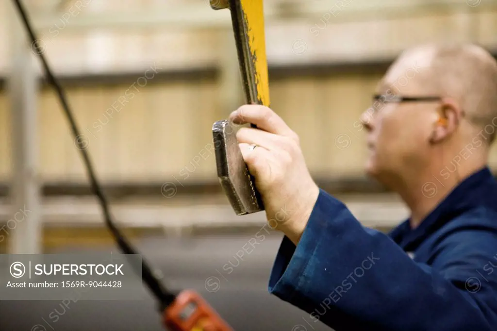 Factory worker operating lift in carpet tile factory