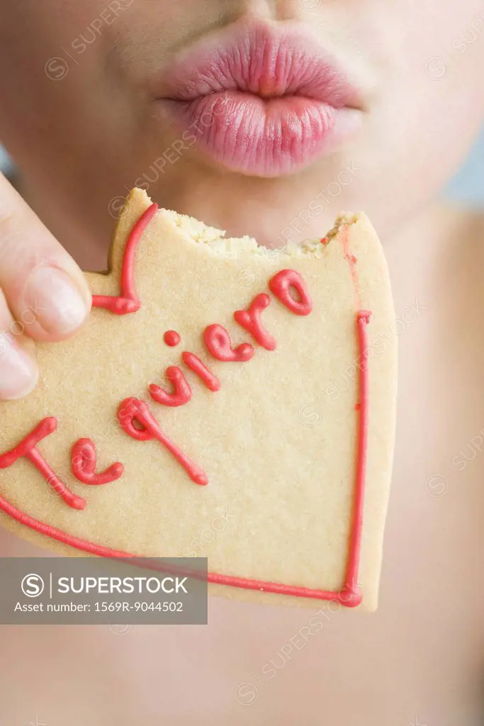 Woman eating heart_shaped cookie, puckering lips