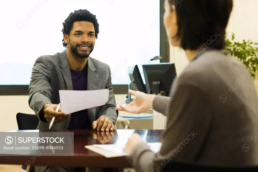 Executive handing document to colleague