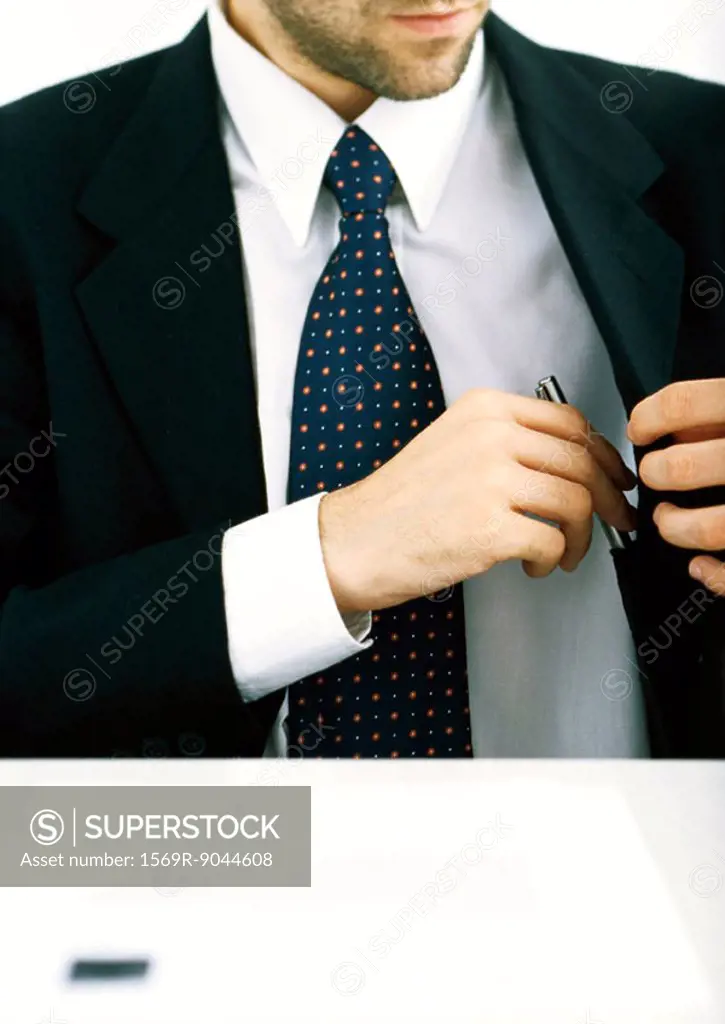 Businessman putting pen into jacket pocket