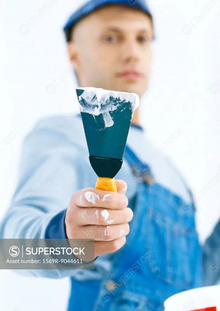 Worker holding out putty knife