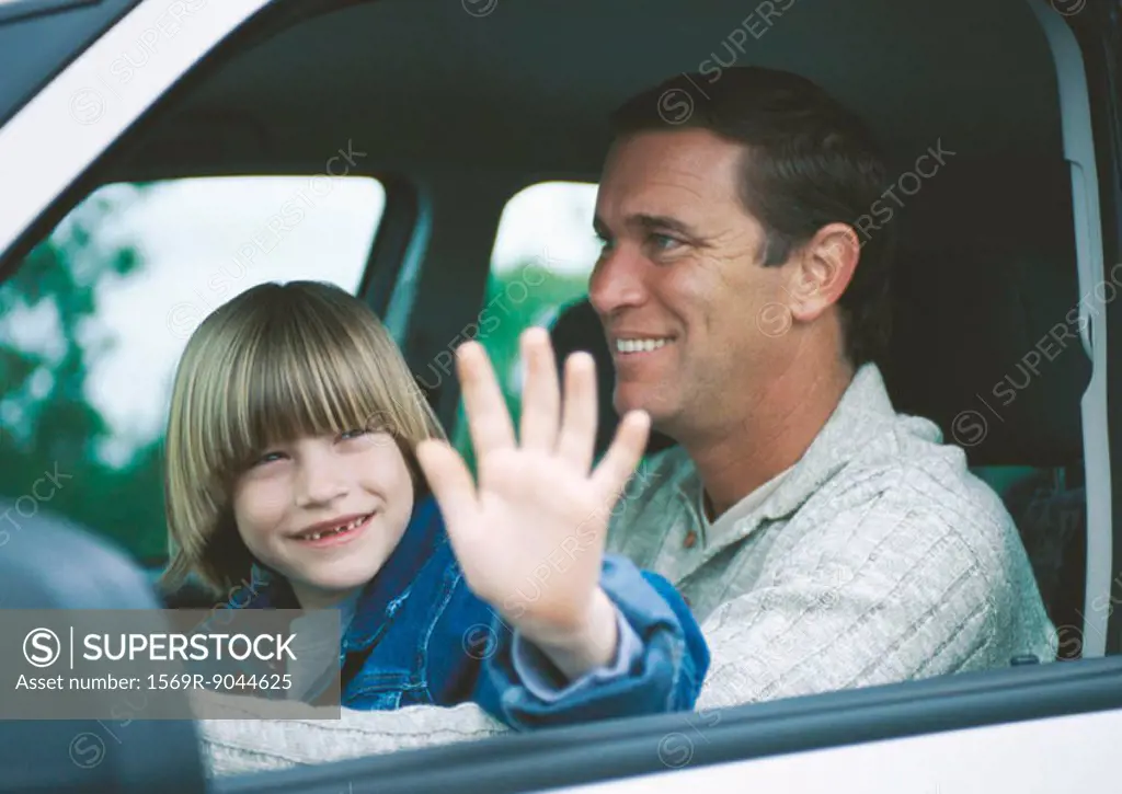 Boy sitting on father´s lap in car