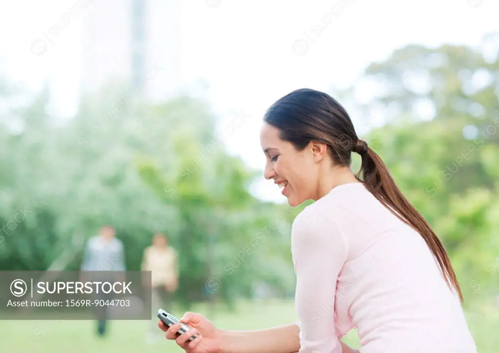 Young woman checking cell phone in city park