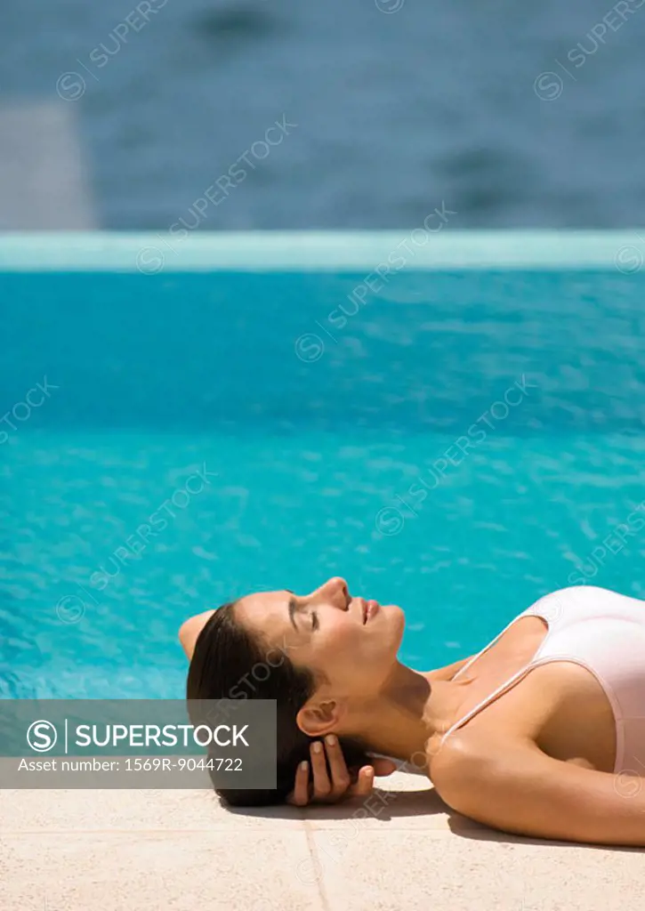 Woman lying on ground near edge of pool