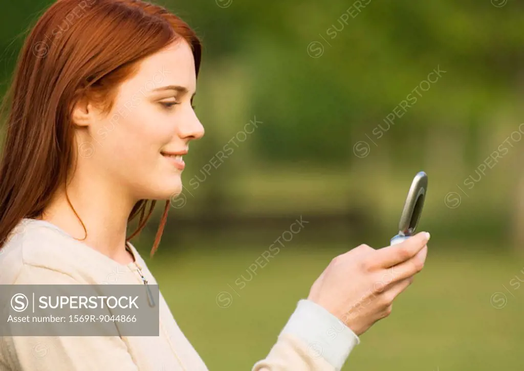 Young woman looking at cell phone, side view
