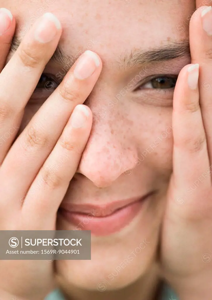 Woman looking through fingers, extreme close-up