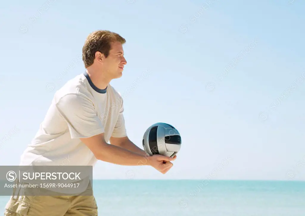 Man serving volleyball on beach