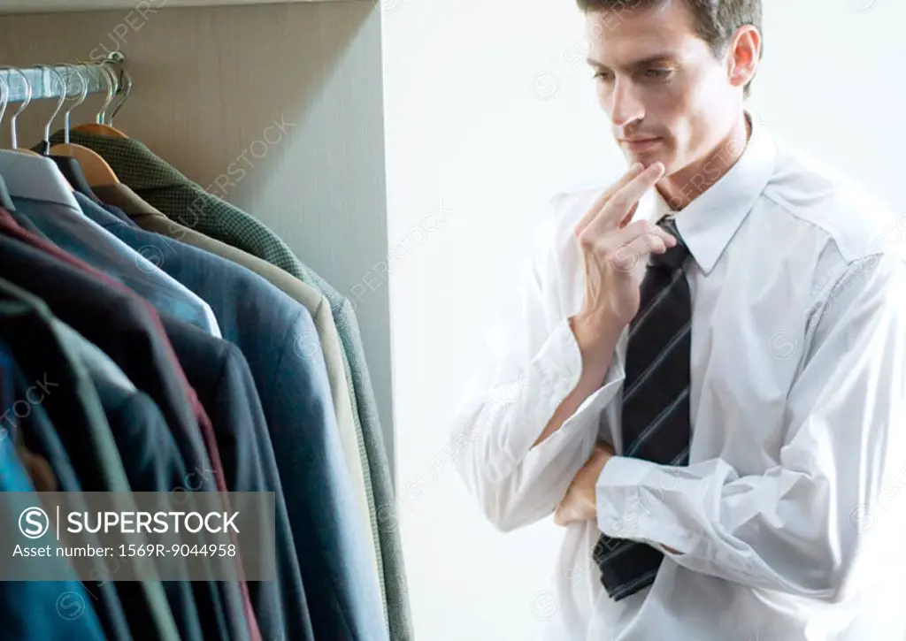 Man choosing jacket from closet
