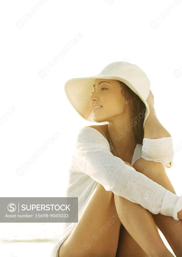 Woman sitting wearing sun hat, looking into distance