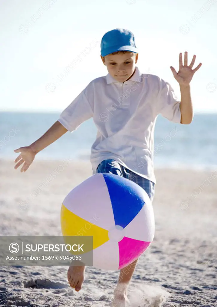 Boy kicking beach ball