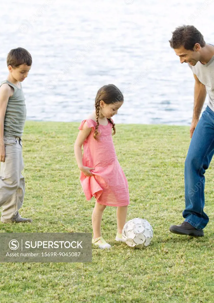 Father playing soccer with children
