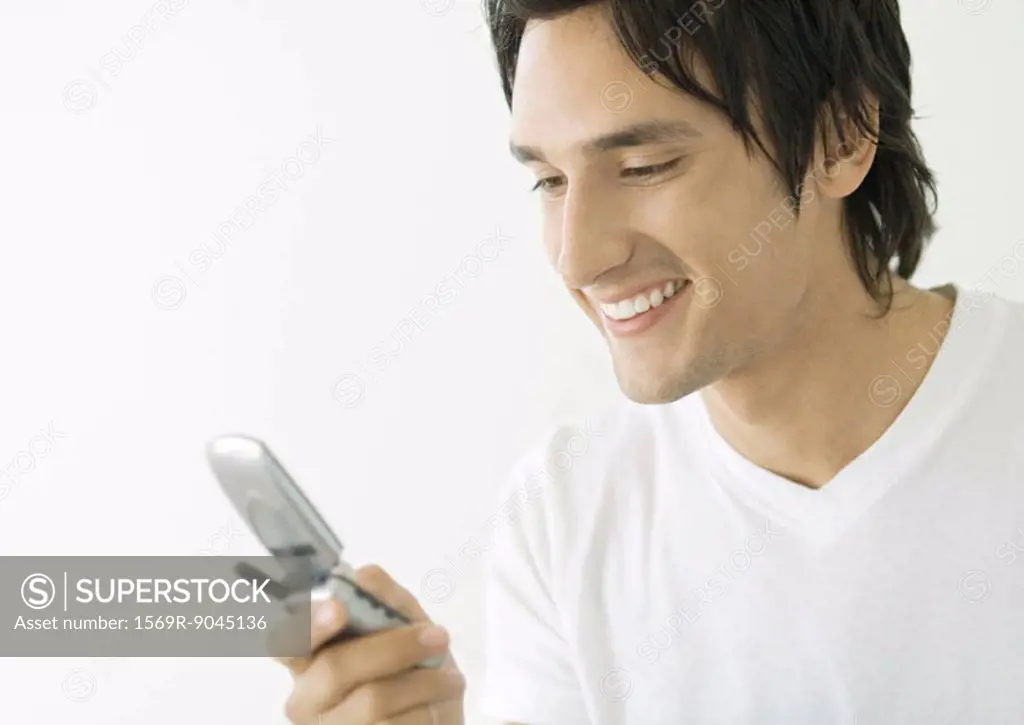 Young man looking at cell phone, smiling