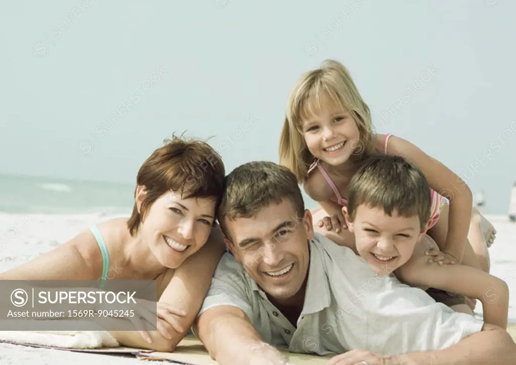 Family lying on beach, smiling, portrait