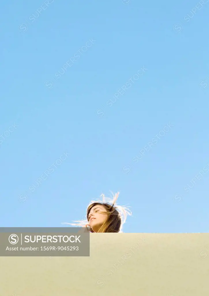 Young woman with hair blowing, low angle view
