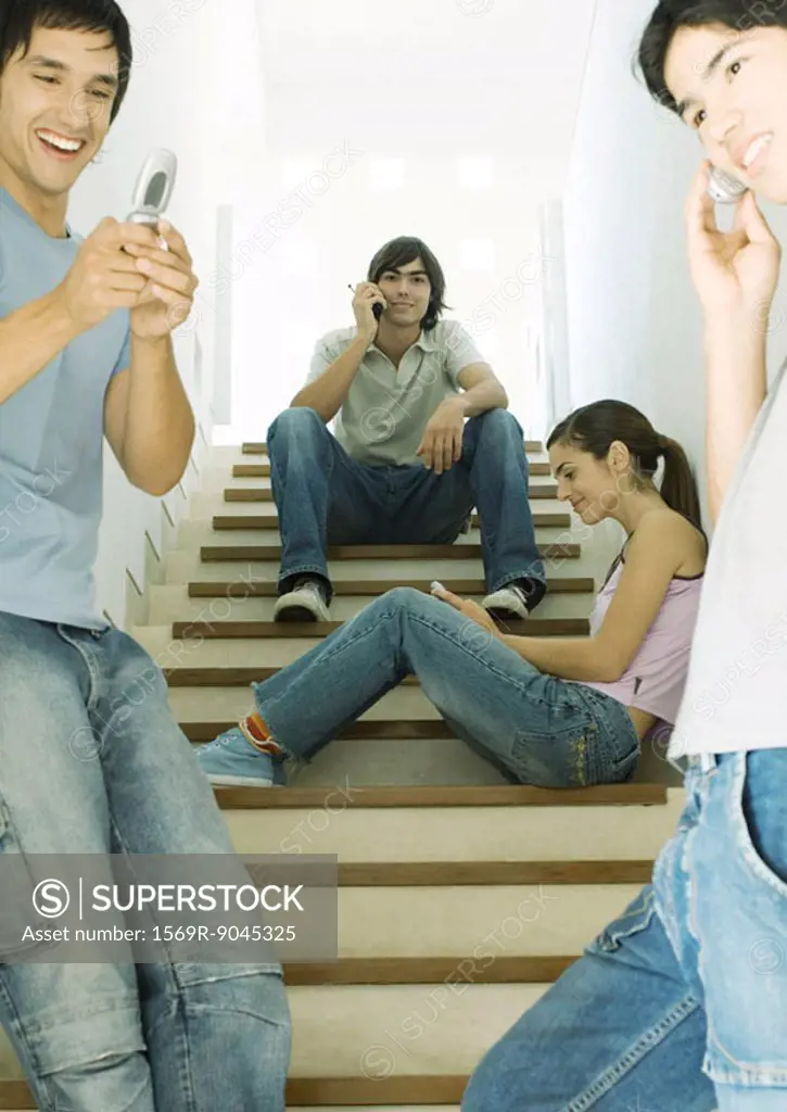 Four young people using cell phones in stairway