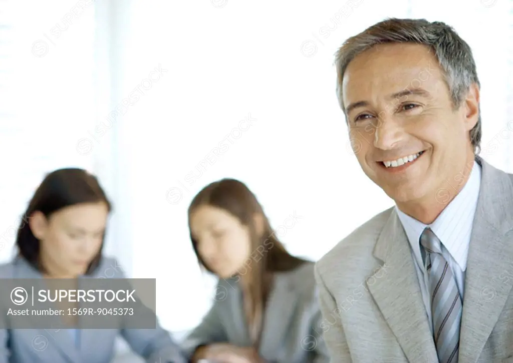 Businessman smiling, colleagues in background