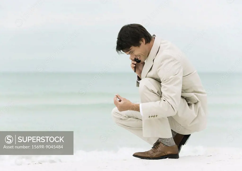 Businessman using cell phone on the beach