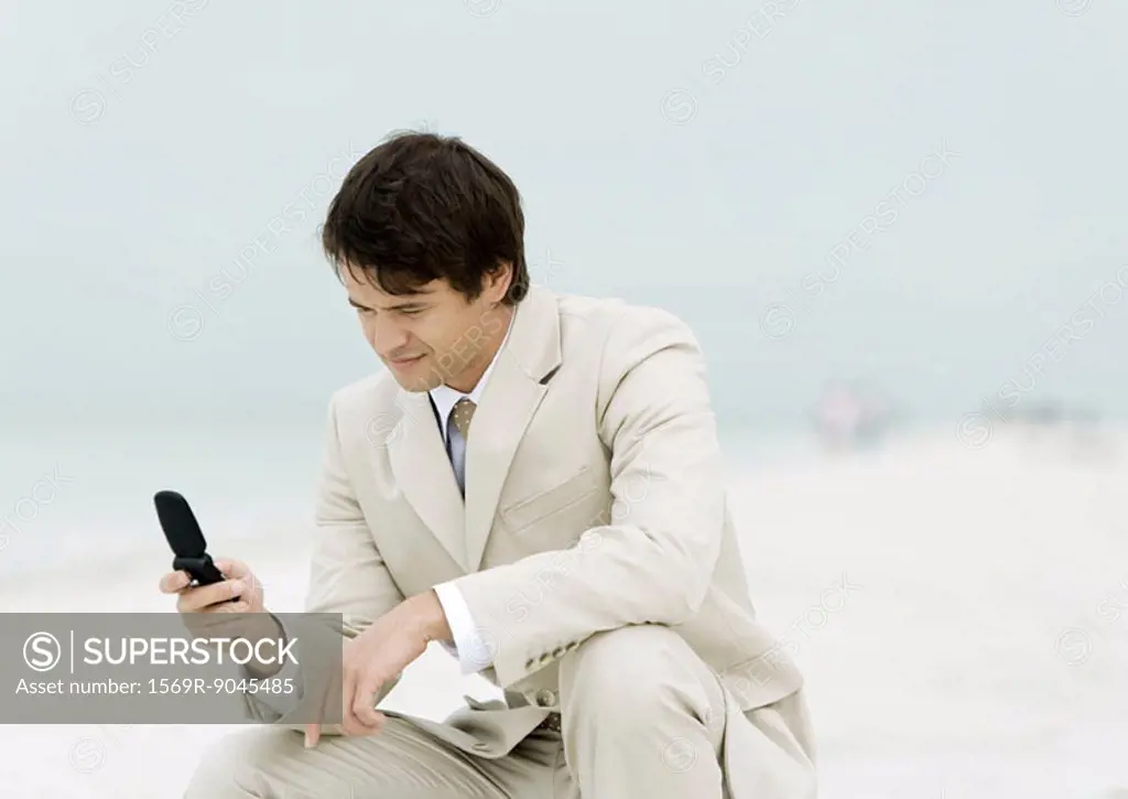 Businessman using cell phone on the beach