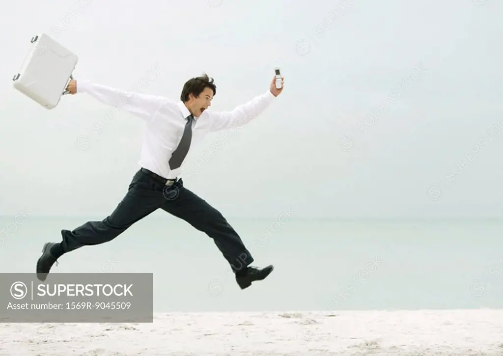 Businessman running and jumping on beach