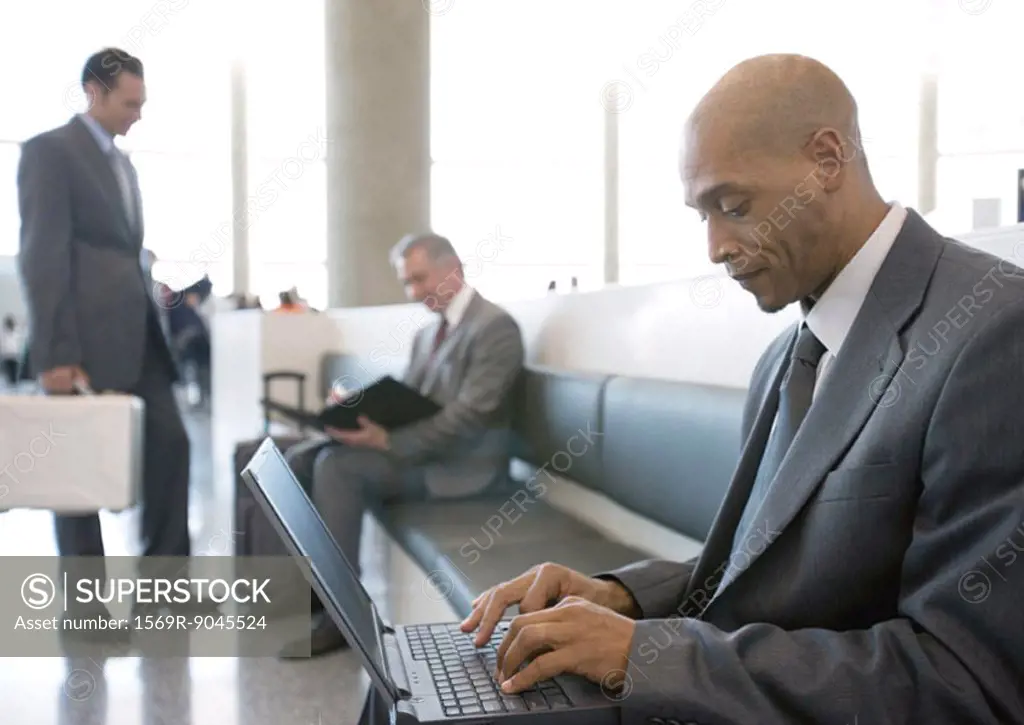Businessman using laptop in airport lounge area