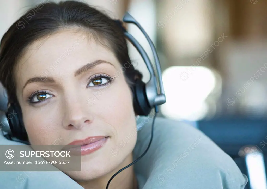 Woman wearing headphones and using neck pillow