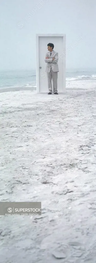On beach, businessman standing in front of closed door