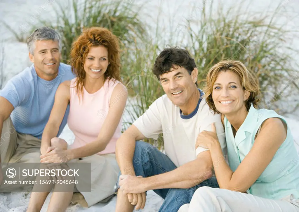 Two mature couples sitting on beach