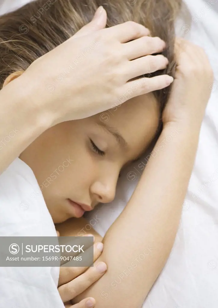 Girl sleeping in bed, mother´s hand stroking head