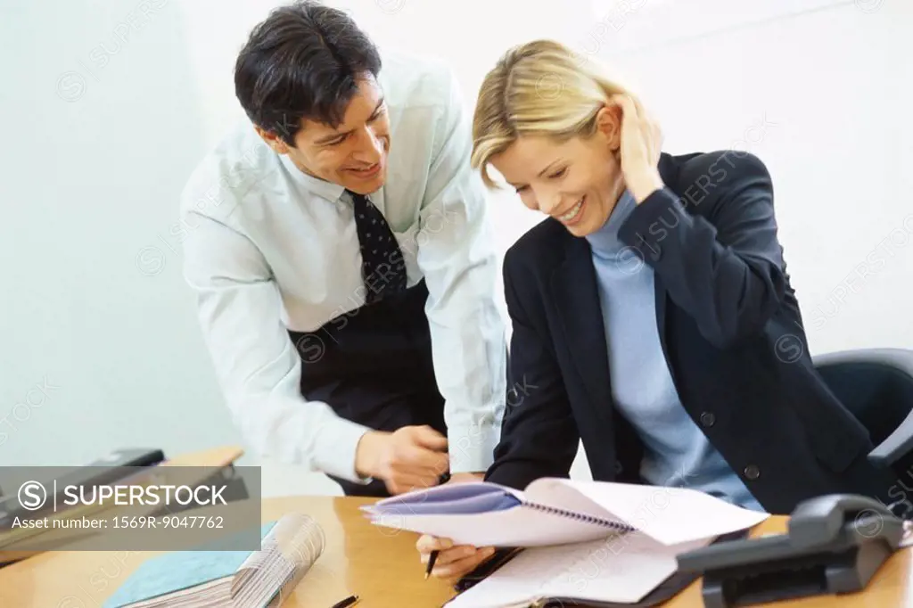 Business colleagues, man leaning over woman´s shoulder, pointing to documents