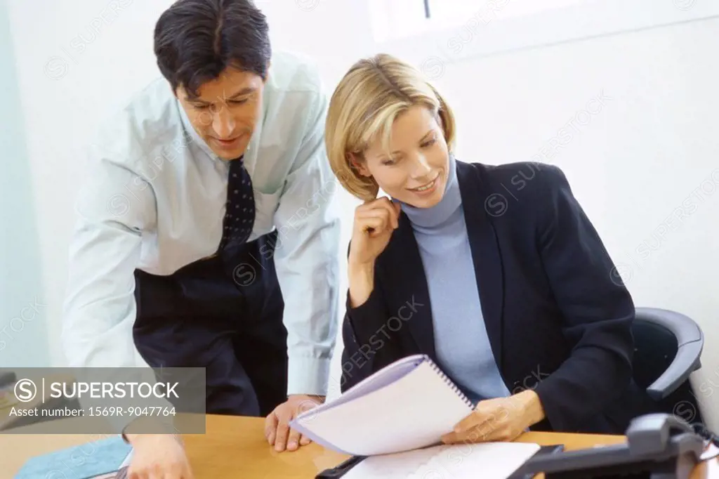 Business colleagues, man leaning over woman´s shoulder, pointing to documents