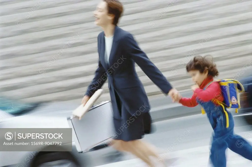 Businesswoman hurrying, holding little boy´s hand