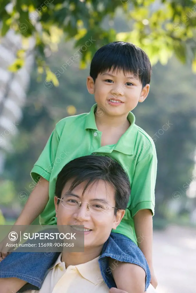 Boy sitting on father´s shoulders, smiling at camera