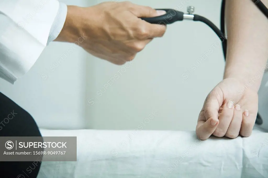 Doctor taking woman´s blood pressure, close-up