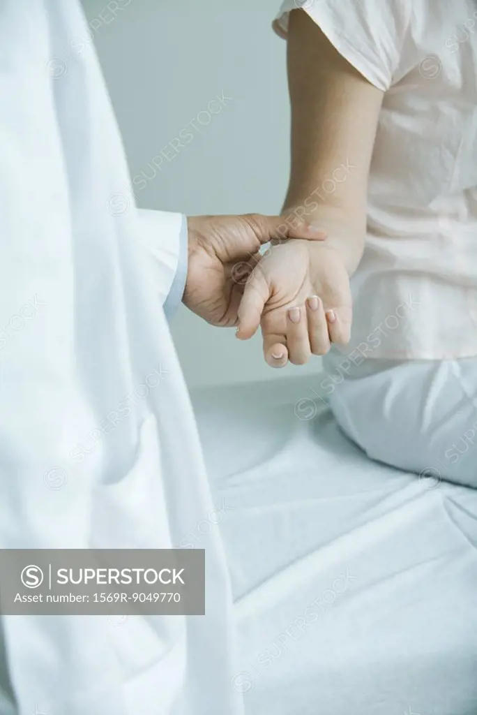 Doctor taking woman´s pulse, close-up