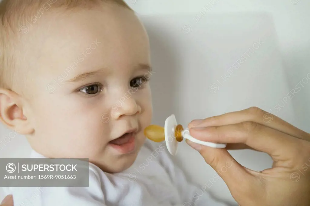 Mother´s hand holding up pacifier for baby