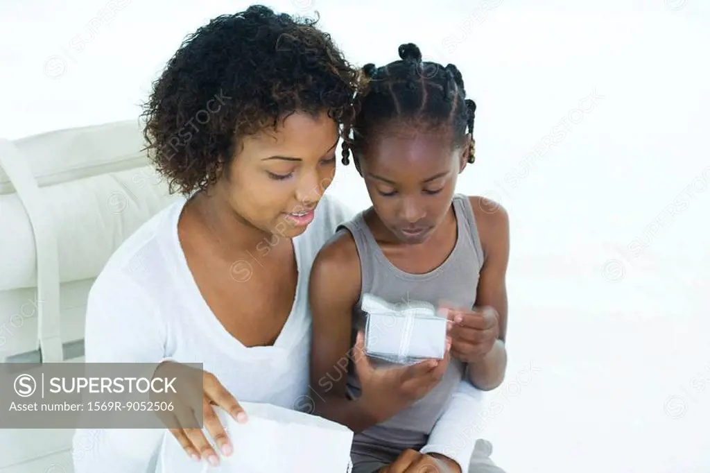 Mother and daughter looking at present, girl sitting on woman´s lap