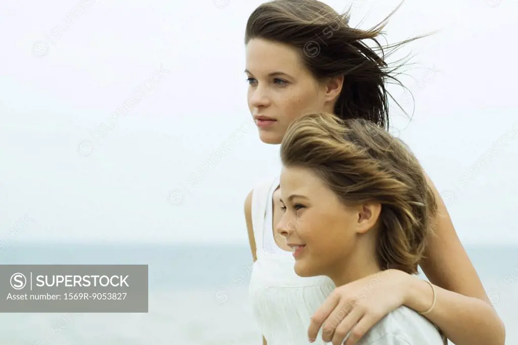 Teenage girl standing with arm around brother´s shoulder, both looking at view
