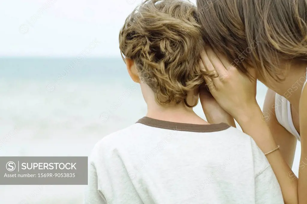 Teenage girl whispering in boy´s ear, cropped rear view