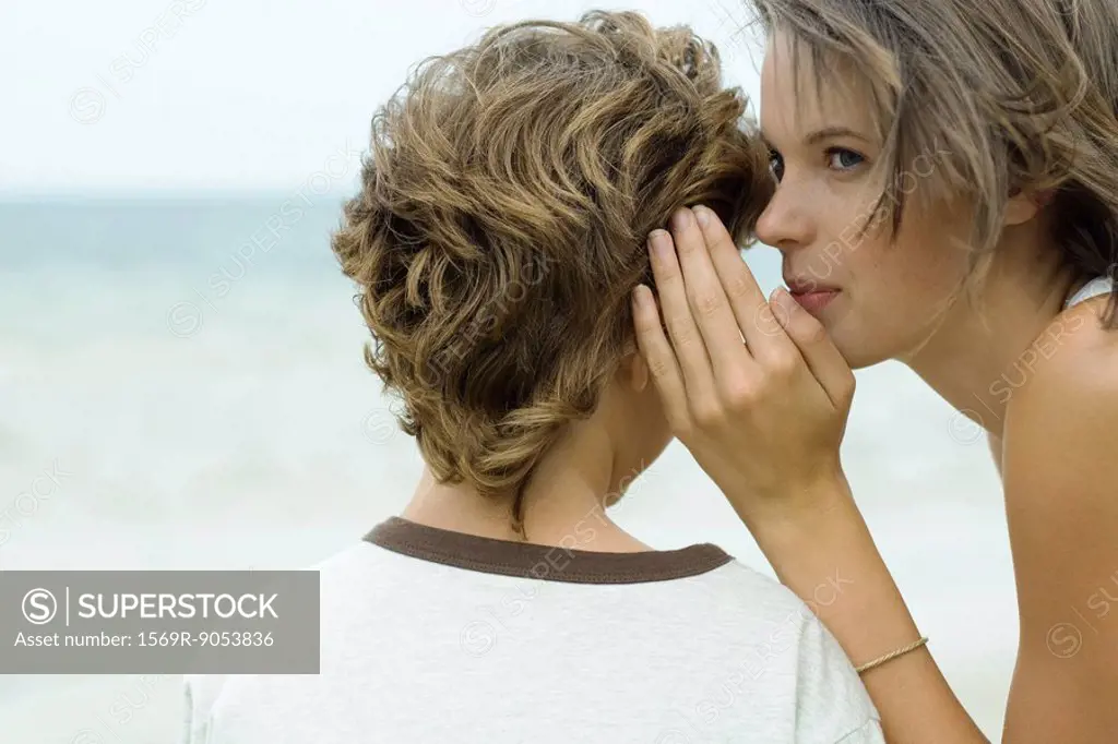 Teenage girl whispering in boy´s ear, cropped view