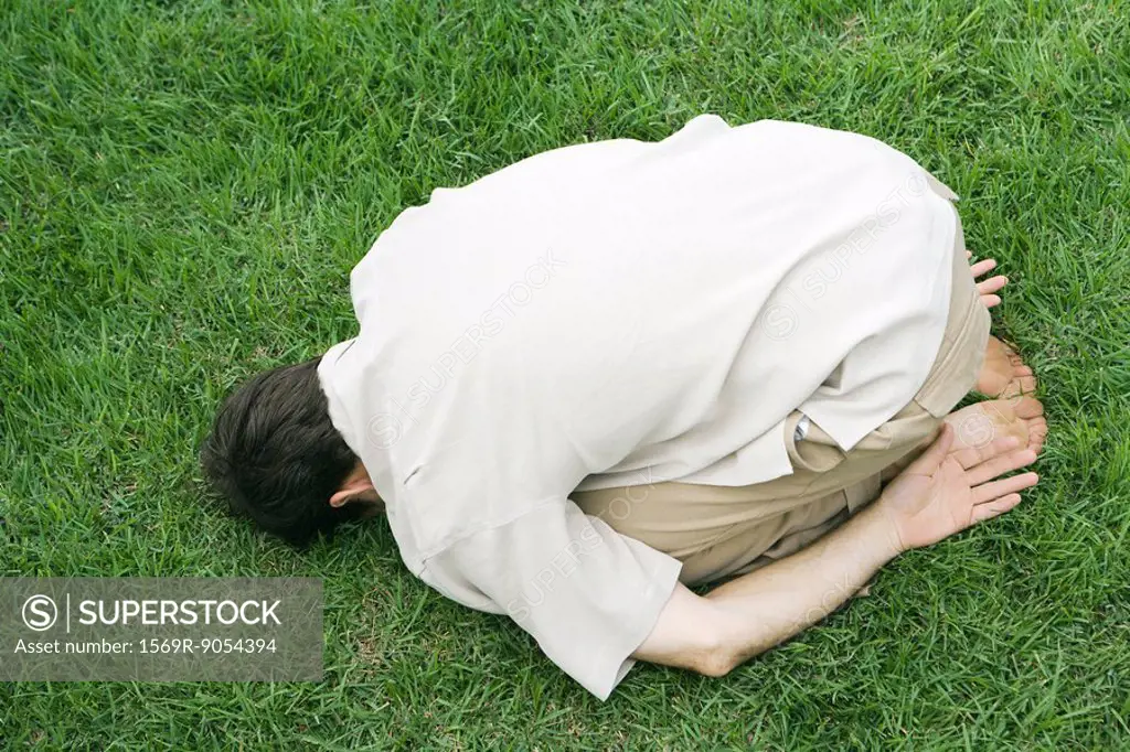 Man doing child´s pose on grass, high angle view