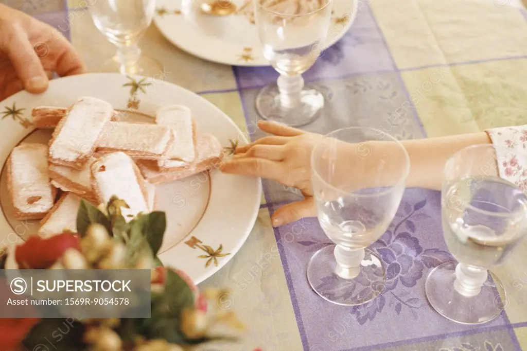 Child reaching for cookies on plate