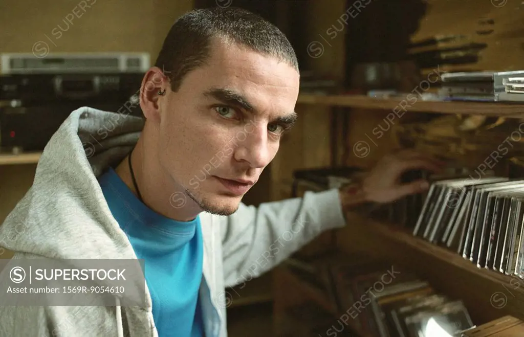 Young man selecting CD from collection on shelf