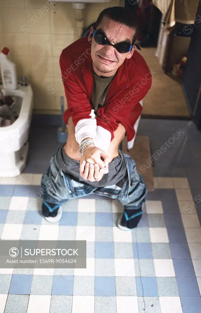 Man using toilet, grimacing