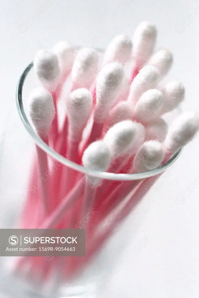 Glass containing supply of pink cotton swabs